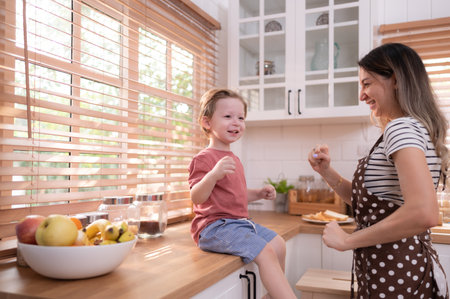 Mother in the kitchen of the house with a small child. Play and have fun cooking dinner together.の写真素材