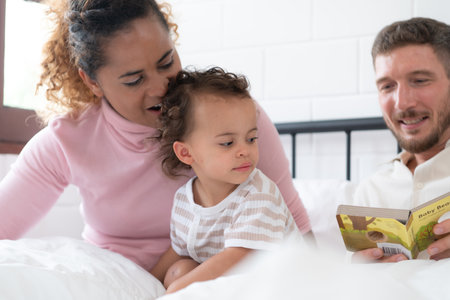 Little girl's father read stories to children before going to bed to unwind and sleep soundly until the morning.の写真素材