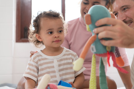 Parents with little girl have fun playing with your new toys in the bedroom together. Toys that enhance children's thinking skills.の写真素材