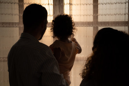 Parents and children enjoy the morning sunlight shining through the bedroom window in the house.の写真素材