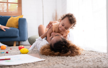 On a vacation morning, parents and children are having fun playing in the living room, with the father hoisting his daughter up behind her mother.の写真素材