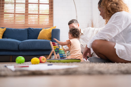 A little girl is having fun with her toys, and her mother is begging her daughter to sing with her.の写真素材