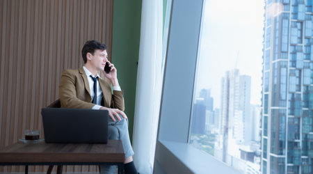 Young businessman sit and relax in the relaxation room by the window overlooking the beautiful city buildings. along with the phone to talk about business.の写真素材