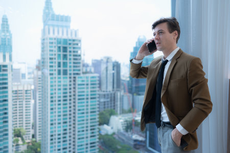 Young businessman sit and relax in the relaxation room by the window overlooking the beautiful city buildings. along with the phone to talk about business.の写真素材