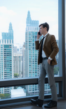 Young businessman sit and relax in the relaxation room by the window overlooking the beautiful city buildings. along with the phone to talk about business.の写真素材