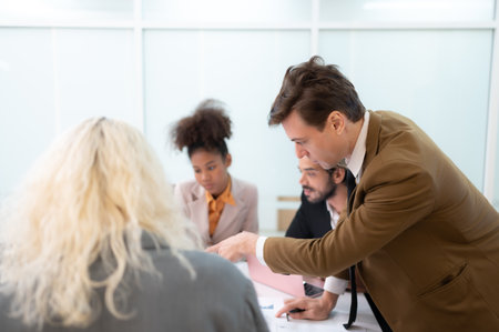 In the meeting room of an international business corporation, a diverse group of young entrepreneurs are enthusiastically taking their ideas and sharing perspectives.の写真素材