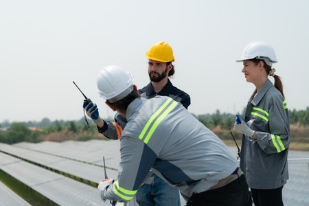 On the rooftop of a large solar energy storage station building A team of electric power engineers inspecting solar panels that have been installed on hundreds of acres of fields.の写真素材