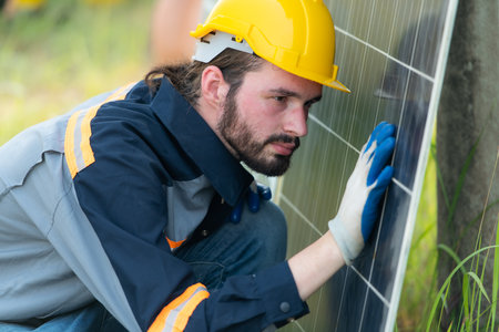 An electrical engineer is inspecting a solar cell that has been used for some time, installed on a field hundred acres of grass.の写真素材