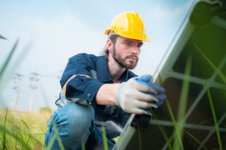 An electrical engineer is inspecting a solar cell that has been used for some time, installed on a field hundred acres of grass.の写真素材