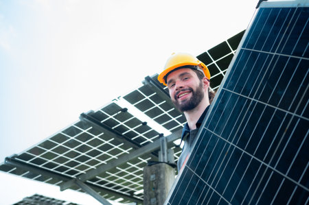 An electrical engineer is inspecting a solar cell that has been used for some time, installed on a field hundred acres of grass.の写真素材