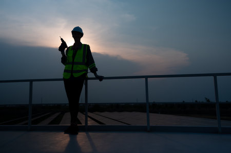 Electrical engineers inspecting solar panels in a hundred acres of grass on the rooftop of energy storage station, in the evening after completing the daily work tasks with the setting sun.の写真素材
