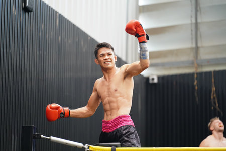 Muay Thai, The martial art of Thailand, Boxer's happiness when he wins by standing on the ropes of the boxing ring and raising his hands and shouting satisfactorilyの写真素材