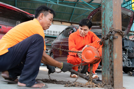 To return the automobile body to its former shape, an auto repair mechanic uses a machine to pull the car body caused by a heavy collision until it is deformed.の写真素材