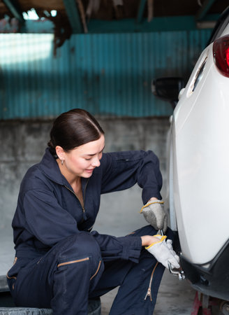 A female mechanic checking the condition of a car's brake discs and the condition of the tires that have been used for a whileの写真素材