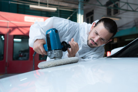 Auto mechanic use an electric polisher to polish the dried car paint. After passing the paint from...