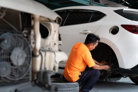 A auto mechanic checking the condition of a car's brake discs and the condition of the tires that have been used for a whileの写真素材