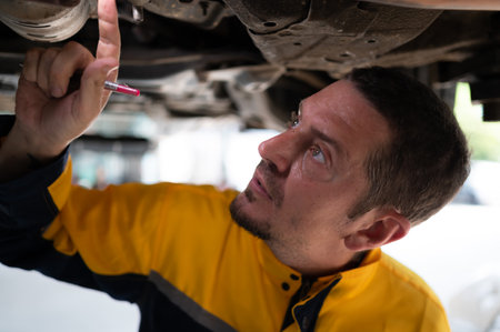 Auto repair mechanic the undercarriage of the car is being inspected for damage caused by heavy collisions.の写真素材