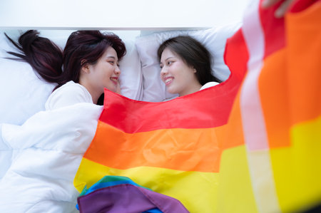 In a hotel bedroom, an LGBT couple snuggled together on the bed happily.の写真素材