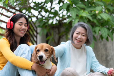 Family vacation, mother, daughter, and beagle puppy relaxing on weekends in the front yard.の写真素材