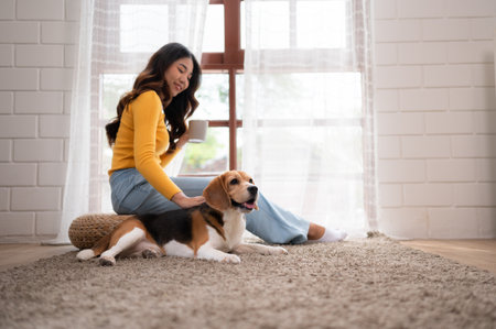 On weekends, a beagle and her owner sit in their living room, sipping coffee and gazing out the window.の写真素材