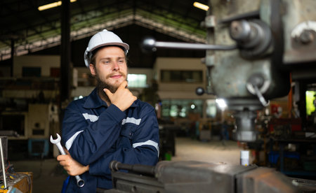 Portrait of mechanical engineers are checking the working condition of an old machine that has been used for some time. In a factory where natural light shines onto the workplaceの写真素材