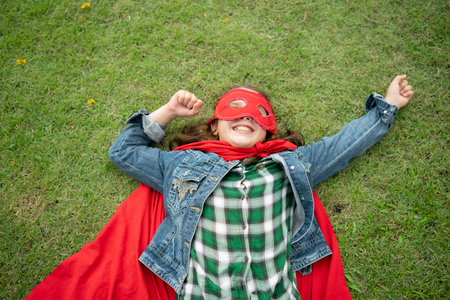 On a beautiful day in the park, a young girl enjoys her vacation. Playful with a red superhero...