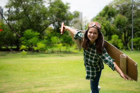 A little girl on vacation at the park with a pilot outfit and flying equipment. Run around and have fun with her dreams.の写真素材