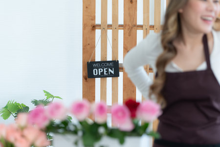 Woman using laptop with open sign in floral shop. Business concept.の写真素材