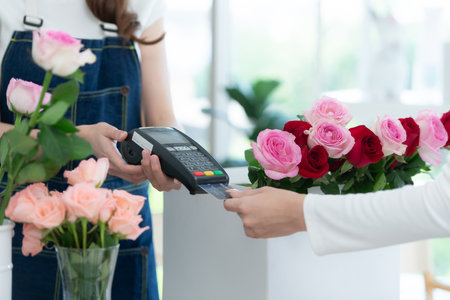Cropped shot of female florist giving credit card to customerの写真素材