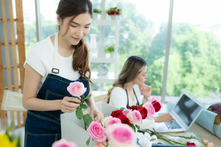 Two asian female florist working at flower shop with laptop.の写真素材