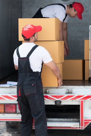 Asian delivery man in uniform delivering package to customer in back of truck.の写真素材