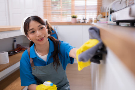 Asian young woman cleaning the countertops cupboard in the kitchen. housework conceptの写真素材