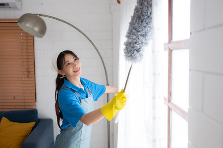 Asian young woman cleaning window in the living room. housework concept