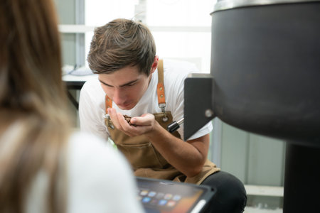 Young man and woman working in coffee beans roaster, They are checking of coffee beans roasted.