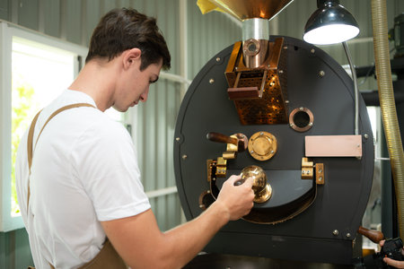 Portrait of a young man working with a coffee roaster machineの写真素材