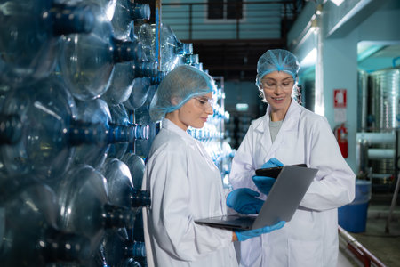 Two young female scientists working with tablet computer in drinking water plant