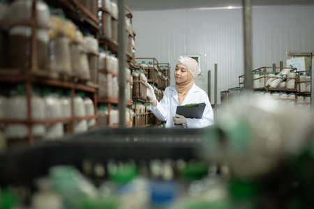 Young asian muslim female scientist doing research at a mushroom factory, examining mushroom leavening agent in a sterile and temperature-controlled room.の写真素材