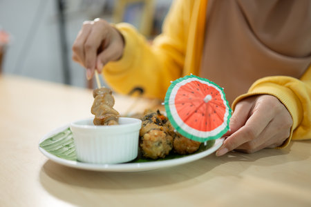 Muslim girl eating mushroom sushi at the restaurant. Selective focus on sushiの写真素材