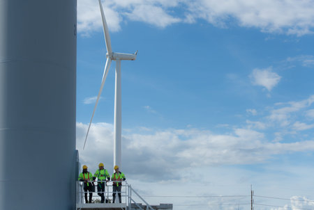 Group of engineers and technicians standing on the stairs of a wind turbine, The concept of natural...