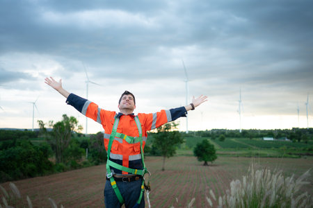 Young engineer working in a wind turbine field wear a safety vest raise both hands to relax after finishing the wind turbine inspection missionの写真素材