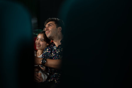 Young man and woman watching movie in cinema, sitting on red seats