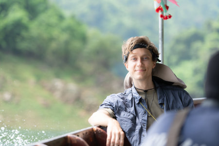 A young man sits on a boat for a journey into the forest above the dam for trekking.の写真素材