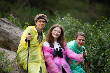 Group of friends in raincoats with backpacks on a hike in the forest, Prepare to hiking after the rain has stopped.の写真素材