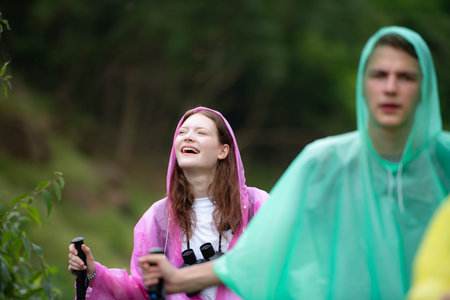 Group of friends in raincoats walking on the forest path, Hiking concept.の写真素材