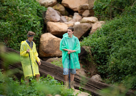 Group of happy friends in raincoats having fun in the forestの写真素材