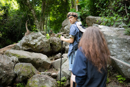 Young couple hiking in forest help each other in the climbing, Man and woman trekking in nature.の写真素材