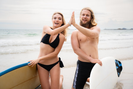 Two surfers giving high five on the beach. Two surfers having fun on the beach.の写真素材
