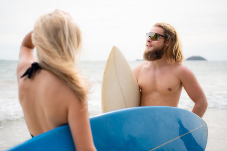 Young man and woman holding surfboards ready to walk into the sea to surf.の写真素材