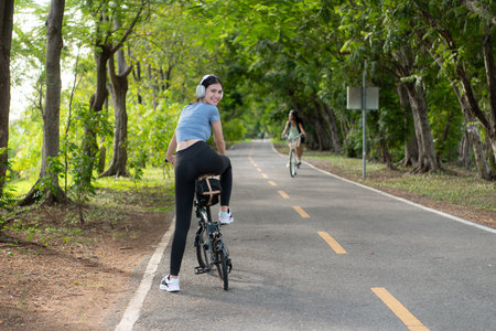Young woman listening to music with headphones while biking in the parkの写真素材