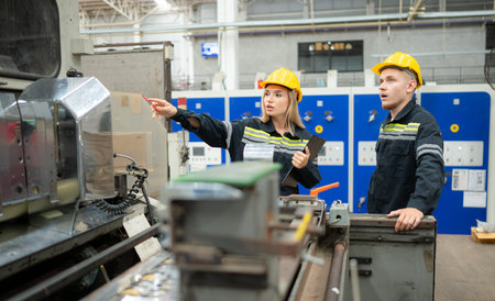 Both of engineer workers working on a machine in a factory. Industrial background